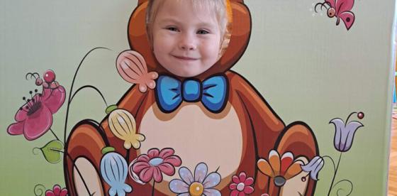 Przedszkolak w fotobudce z wizerunkiem pluszowego misia